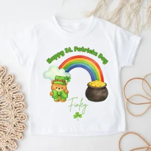 Personalised Happy St Patrick’s Day children’s t-shirt with rainbow and teddy bear design, name Finley, flatlay on white background