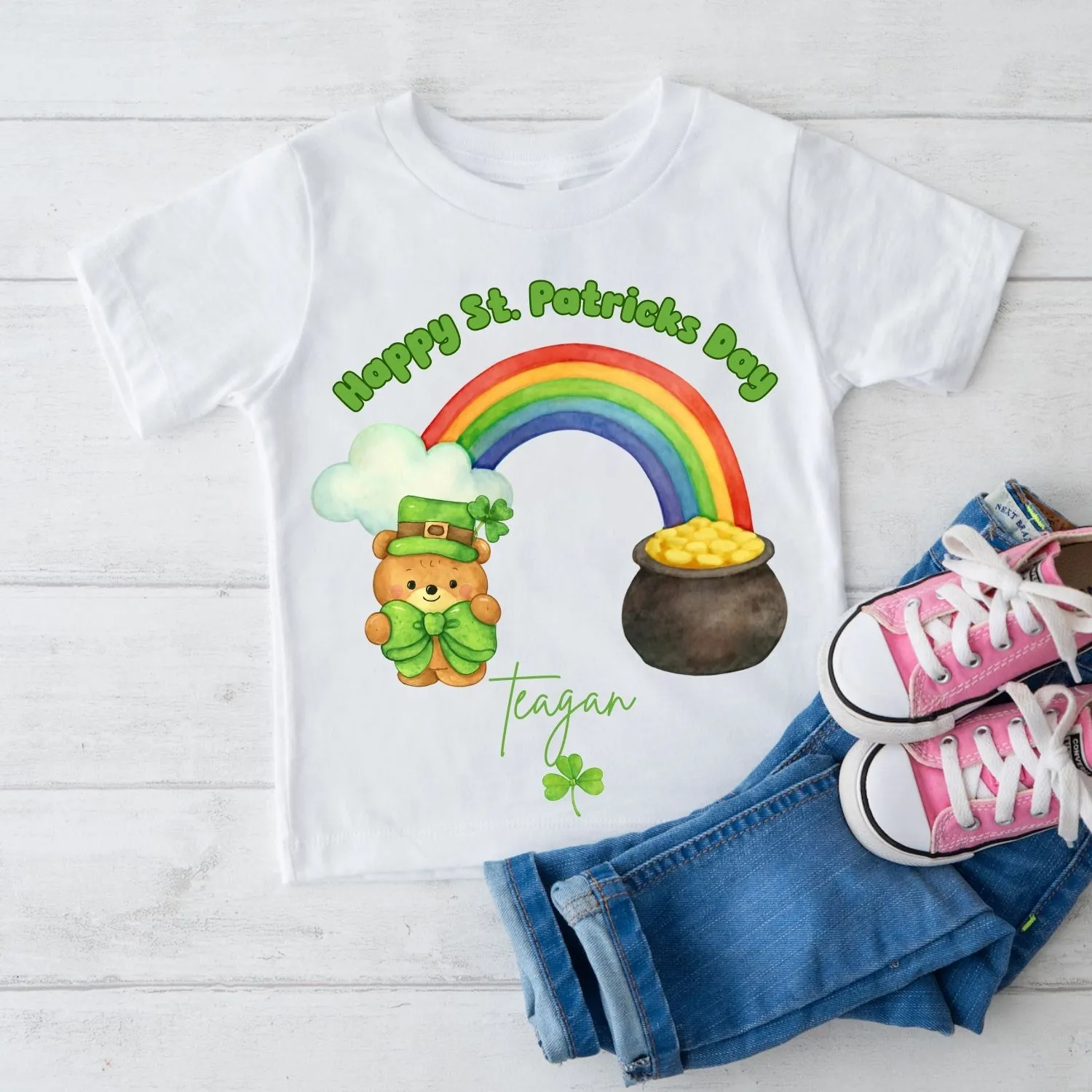 Personalised St Patrick’s Day kids t-shirt with rainbow and pot of gold design, name Finley, styled flatlay with jeans and trainers
