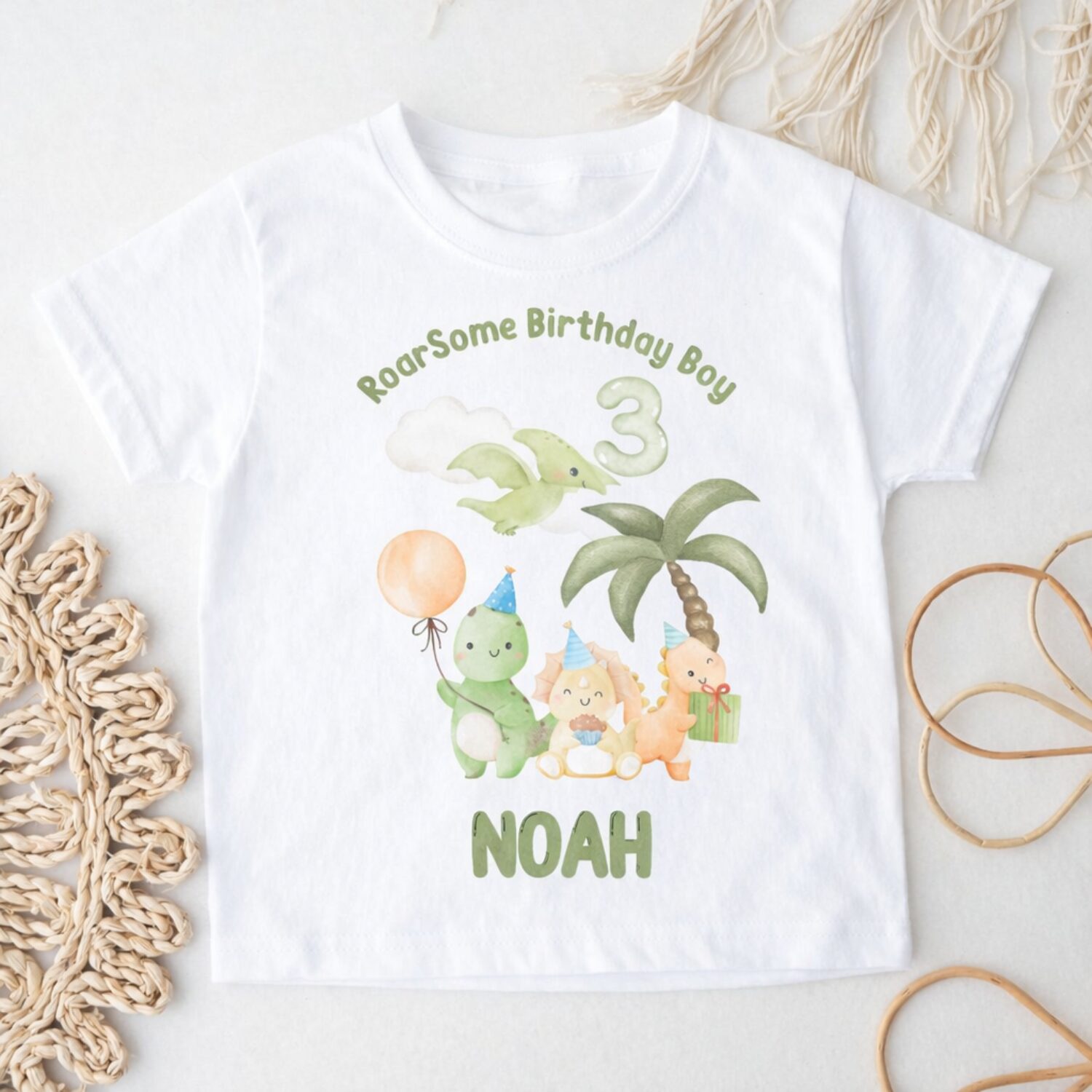 Flat lay personalised dinosaur birthday shirt featuring cute watercolour dinosaurs