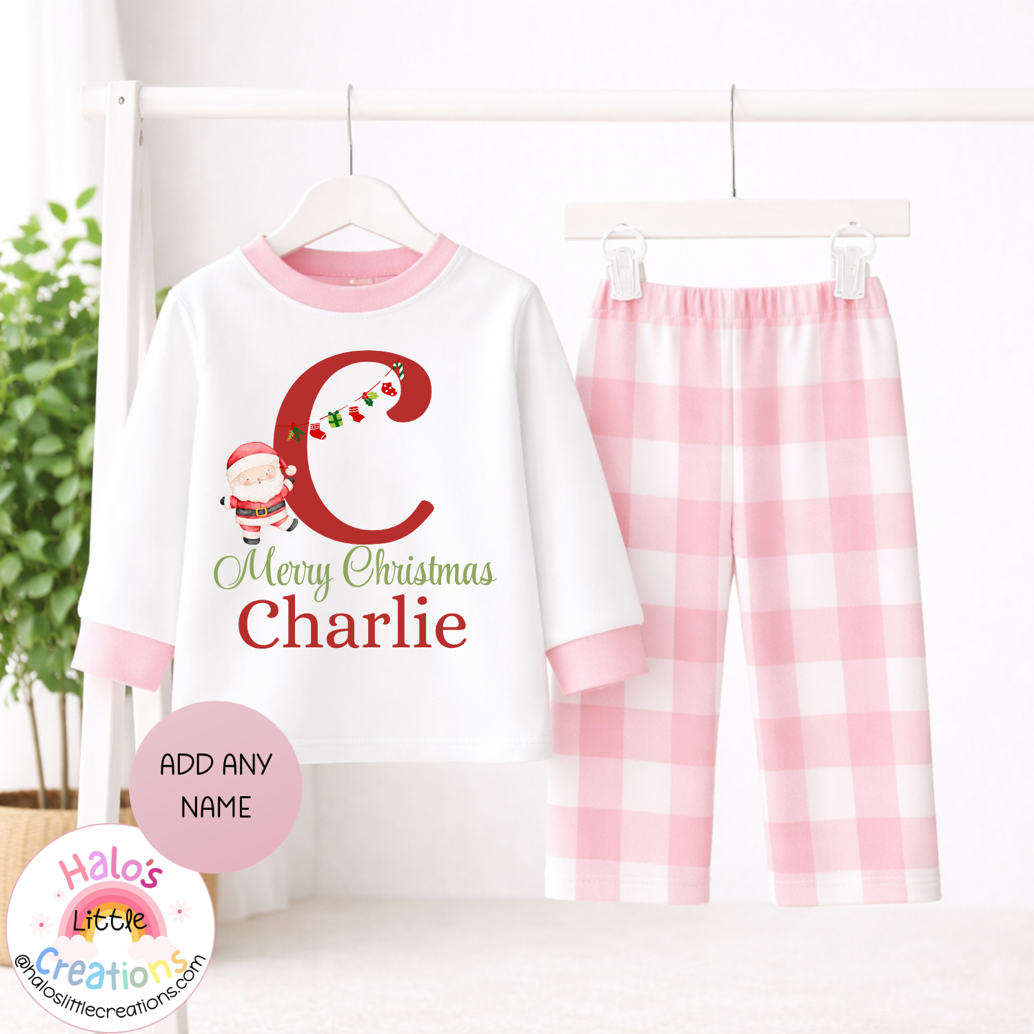Personalised pink checked Christmas pyjama set with white top, pink cuffs, Santa initial design and child's name Charlie.