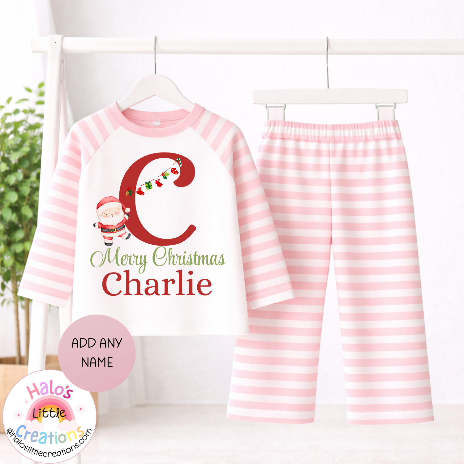 Personalised girls Christmas pyjamas featuring pink and white striped sleeves and trousers, festive red initial, Santa and name Charlie.